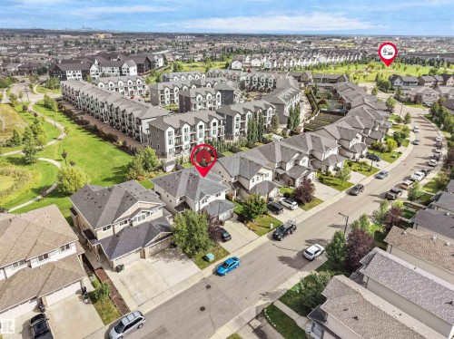 Residential neighborhood with varied housing styles including single-family homes and multi-story townhomes, surrounded by green spaces and paved roadways - 6656 Cardinal Rd Sw, Edmonton, AB 