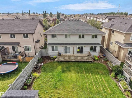 Expansive backyard featuring a manicured lawn, wood deck, and partial privacy fencing - 6656 Cardinal Rd Sw, Edmonton, AB 