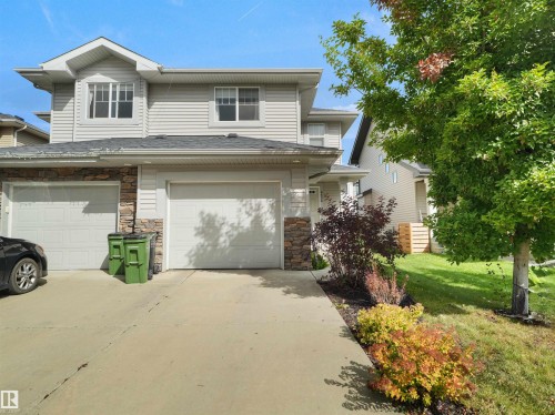 Light-toned siding exterior with stone accents, attached two-car garage, and established front landscaping - 6656 Cardinal Rd Sw, Edmonton, AB 