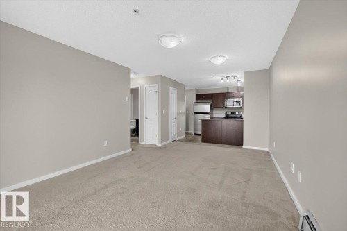 Open-concept living area featuring neutral carpeting and light-toned walls - #316 392 Silver Berry Rd Nw, Edmonton, AB - Indoor