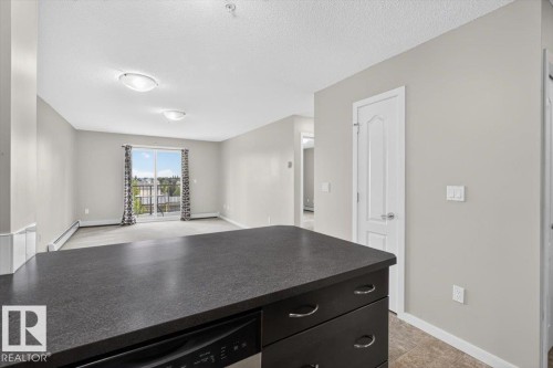 Kitchen island with a dark countertop and integrated dishwasher - #316 392 Silver Berry Rd Nw, Edmonton, AB - Indoor Photo Showing Other Room