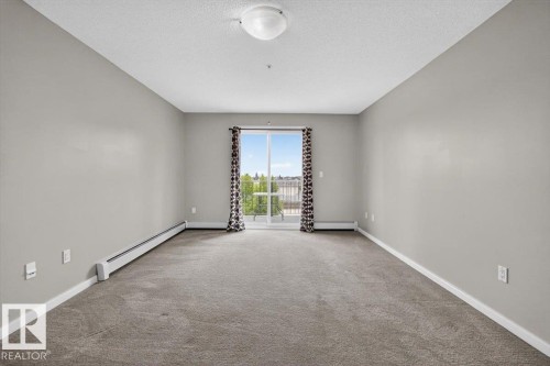 Carpeted room with a sliding glass door opening to an exterior balcony - #316 392 Silver Berry Rd Nw, Edmonton, AB - Indoor Photo Showing Other Room
