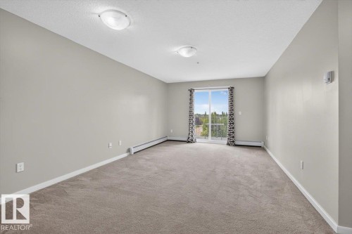 Spacious room featuring neutral carpeting, light-toned walls, and a glass-paned sliding door with curtains - #316 392 Silver Berry Rd Nw, Edmonton, AB - Indoor Photo Showing Other Room