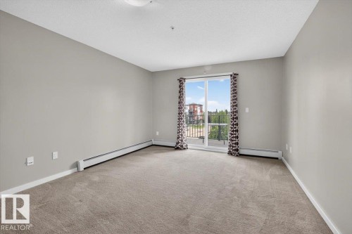 Spacious room featuring neutral paint, carpeted flooring, and a sliding glass door leading to an outdoor balcony - #316 392 Silver Berry Rd Nw, Edmonton, AB - Indoor Photo Showing Other Room