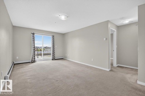Spacious living area featuring neutral carpeting, light gray wall paint, and white trim - #316 392 Silver Berry Rd Nw, Edmonton, AB - Indoor Photo Showing Other Room