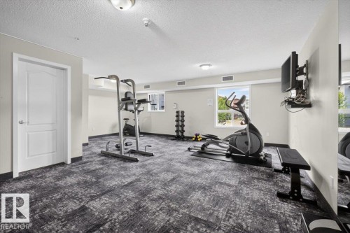 Spacious fitness area featuring patterned carpet flooring, multiple windows providing natural light, and recessed ceiling lighting - #316 392 Silver Berry Rd Nw, Edmonton, AB - Indoor Photo Showing Gym Room