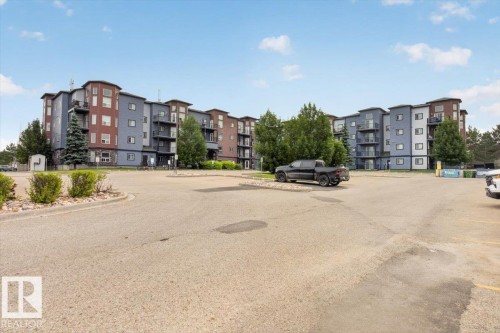 Multi-story residential building with a contemporary facade featuring varying shades of blue and brown panels - #316 392 Silver Berry Rd Nw, Edmonton, AB - Outdoor With Facade