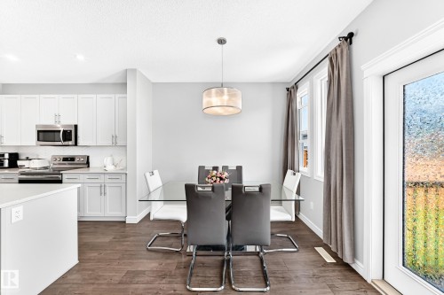 Wood-finish flooring throughout, with a drum pendant light fixture, and white cabinetry - 2628 Donaghey Crescent Sw, Edmonton, AB 