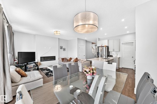 Open-concept living space featuring wood-finish flooring, recessed lighting, and a linear electric fireplace - 2628 Donaghey Crescent Sw, Edmonton, AB 