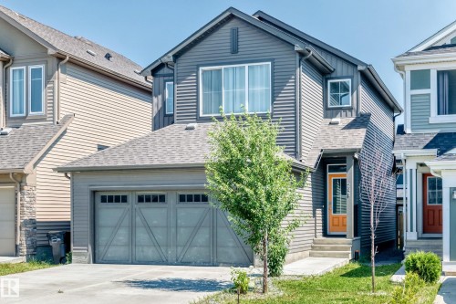 Two-story residence featuring a two-car garage, gray horizontal siding, and a contrasting orange front door - 2628 Donaghey Crescent Sw, Edmonton, AB 
