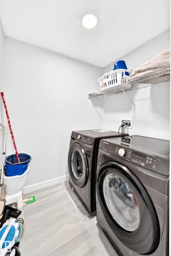 Laundry area with a permanent wire shelf, wall-mounted light fixture, and tile flooring - 2628 Donaghey Crescent Sw, Edmonton, AB 