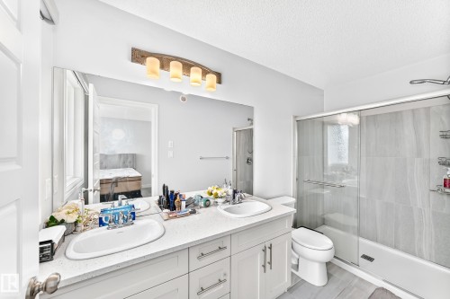 Dual vanity with undermount sinks, stone countertop, and white cabinetry - 2628 Donaghey Crescent Sw, Edmonton, AB 