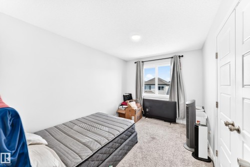 Recessed ceiling lighting, white paneled door, window with dark curtain rods, and textured carpet flooring - 2628 Donaghey Crescent Sw, Edmonton, AB 