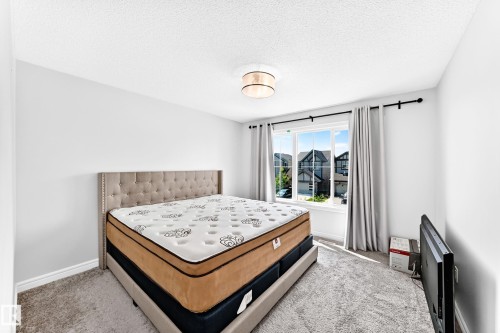 Bright room featuring a large window, neutral wall paint, and a textured ceiling - 2628 Donaghey Crescent Sw, Edmonton, AB 
