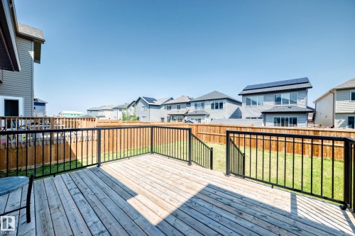 Wood deck with black metal railings, leading to a fenced backyard with a grassy lawn - 2628 Donaghey Crescent Sw, Edmonton, AB 