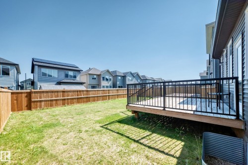 Expansive green space featuring a wooden privacy fence, a raised wooden deck with black metal railings, and siding exterior - 2628 Donaghey Crescent Sw, Edmonton, AB 