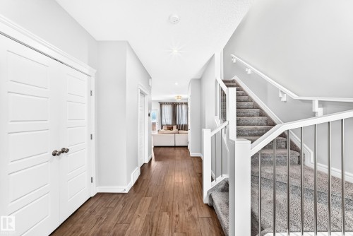 Wood-finish flooring, white paneled doors, carpeted staircase, white newel posts, and metal balusters - 2628 Donaghey Crescent Sw, Edmonton, AB 