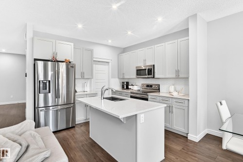Kitchen featuring stainless steel appliances, light gray cabinetry, white countertops, and a central island with an undermount sink - 2628 Donaghey Crescent Sw, Edmonton, AB 