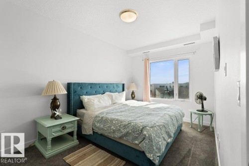 Bright bedroom featuring a large window, neutral wall paint, and gray carpet flooring - 1316 Windermere Way Sw, Edmonton, AB 