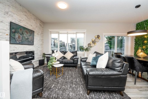 Living space featuring a stacked stone accent wall, linear fireplace, and large windows - 9232 224 St Nw Nw, Edmonton, AB 