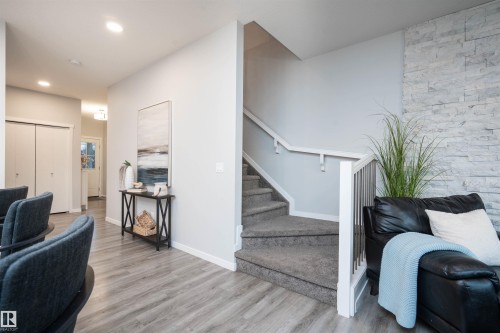 Wood-finish flooring, recessed ceiling lighting, staircase with carpeted treads and white railings, and an accent wall featuring stacked stone - 9232 224 St Nw Nw, Edmonton, AB 