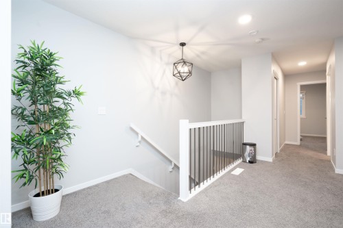 Carpeted landing with white walls, recessed lighting, and a geometric pendant light fixture - 9232 224 St Nw Nw, Edmonton, AB 
