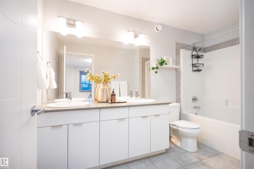 Double vanity with undermount sinks and chrome fixtures, ample white cabinetry, and a bathtub with a tiled shower surround - 9232 224 St Nw Nw, Edmonton, AB 