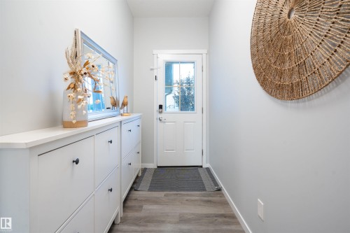 Entryway featuring a white door with a windowpane, light wood-finish flooring, and light gray walls - 9232 224 St Nw Nw, Edmonton, AB 