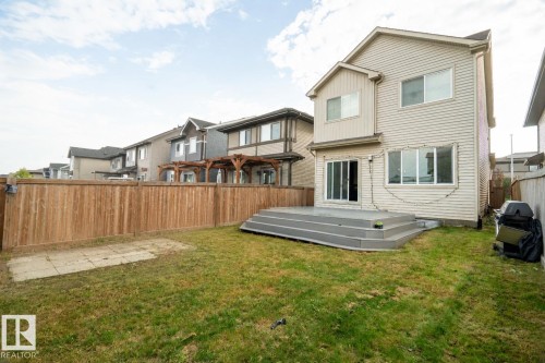 Expansive backyard featuring a tiered deck, sliding glass door access, and a wood privacy fence - 9232 224 St Nw Nw, Edmonton, AB 