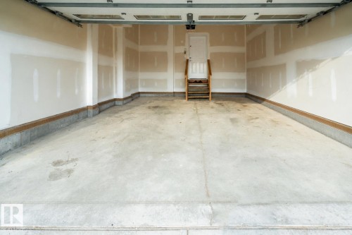 Concrete flooring with a finished concrete perimeter, unfinished drywall, and a white interior door with wood steps AI - 9232 224 St Nw Nw, Edmonton, AB 