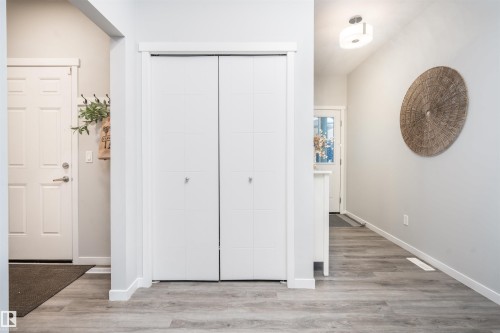 Entryway featuring wood-finish flooring, white paneled doors, and a flush mount ceiling light fixture - 9232 224 St Nw Nw, Edmonton, AB 
