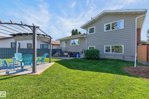 Expansive backyard featuring a lush lawn, a patio, and a pergola with a concrete base - 18316 71 Avenue Nw, Edmonton, AB 