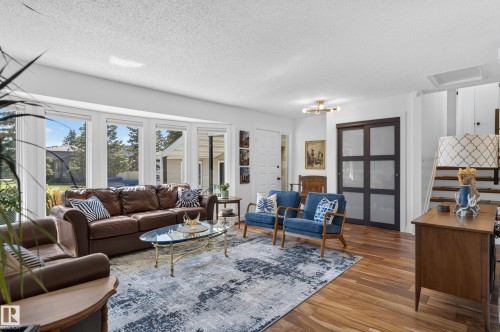 Hardwood flooring, bay window, white paneled door, modern sliding glass panel doors, and a contemporary ceiling light fixture - 18316 71 Avenue Nw, Edmonton, AB 
