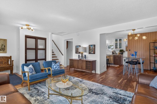 Wood-finish flooring throughout, with a staircase featuring a dark handrail - 18316 71 Avenue Nw, Edmonton, AB 