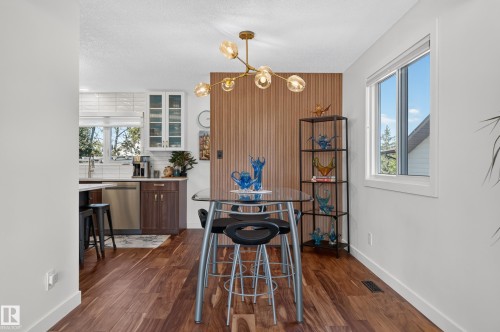 Modern light fixture, wood-finish flooring, white walls, and a wood-slat accent wall - 18316 71 Avenue Nw, Edmonton, AB 