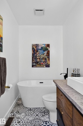 Freestanding soaking tub, patterned floor tile, white floating vanity, rectangular vessel sink, and matte black faucet - 18316 71 Avenue Nw, Edmonton, AB 
