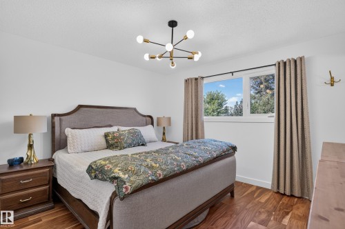 Hardwood-finish flooring, a modern sputnik chandelier, and a large window with white trim - 18316 71 Avenue Nw, Edmonton, AB 