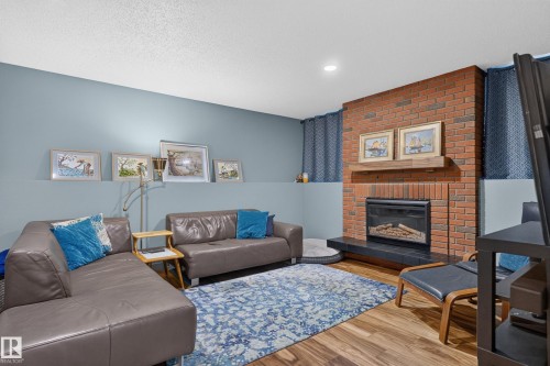 Brick fireplace with an integrated mantel, black hearth, wood-finish flooring, recessed lighting, and a two-tone wall finish - 18316 71 Avenue Nw, Edmonton, AB 