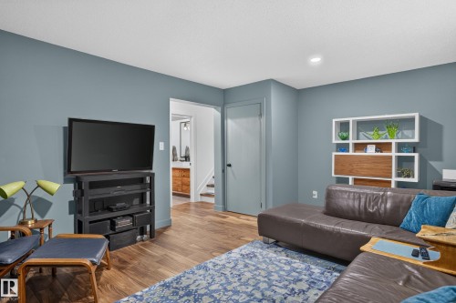 Recessed lighting illuminates the room, featuring wood-finish flooring and a built-in shelving unit - 18316 71 Avenue Nw, Edmonton, AB 