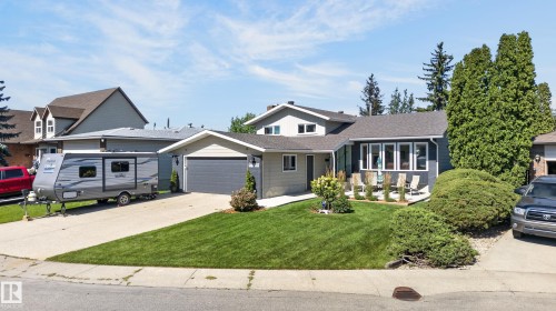 Siding exterior with stone accents, attached garage, extended driveway, front patio, and landscaped front yard - 18316 71 Avenue Nw, Edmonton, AB 