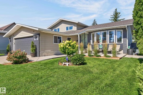 Front exterior featuring light-colored siding, dark brick accents, and a paved driveway - 18316 71 Avenue Nw, Edmonton, AB 
