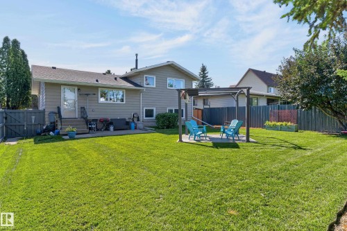 Expansive grassy yard featuring a concrete patio, wooden deck, and a pergola with a concrete base - 18316 71 Avenue Nw, Edmonton, AB 