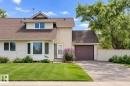 Exterior featuring stucco and siding, a dormer window, a front entry, a garage, and a paved driveway - 9503 180A Street Nw, Edmonton, AB 