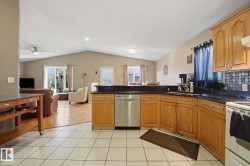Kitchen featuring wood cabinetry, dark countertops, tile flooring, and a stainless steel dishwasher - 