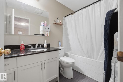 White vanity with dark countertop, undermount sink, and chrome faucet - 5132 157 Avenue Nw, Edmonton, AB 