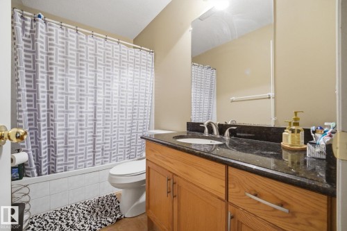 Vanity with a dark countertop and integrated sink, chrome faucet, and wood-finish cabinetry - 5132 157 Avenue Nw, Edmonton, AB 
