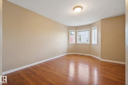 Wood-finish flooring with a multi-pane bay window and neutral wall tones - 5132 157 Avenue Nw, Edmonton, AB 
