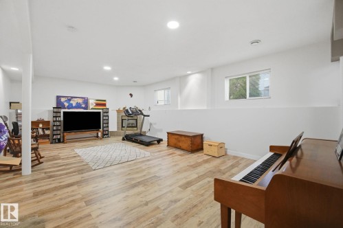 Spacious lower-level room featuring wood-finish flooring, recessed lighting, and a window - 5132 157 Avenue Nw, Edmonton, AB 