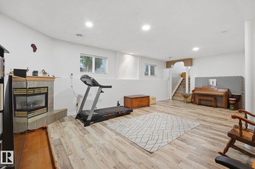 Lower-level living area with recessed lighting, wood-finish flooring, and a corner fireplace with a tiled surround - 5132 157 Avenue Nw, Edmonton, AB 