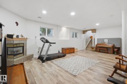 Lower-level living area with recessed lighting, wood-finish flooring, and a corner fireplace with a tiled surround - 